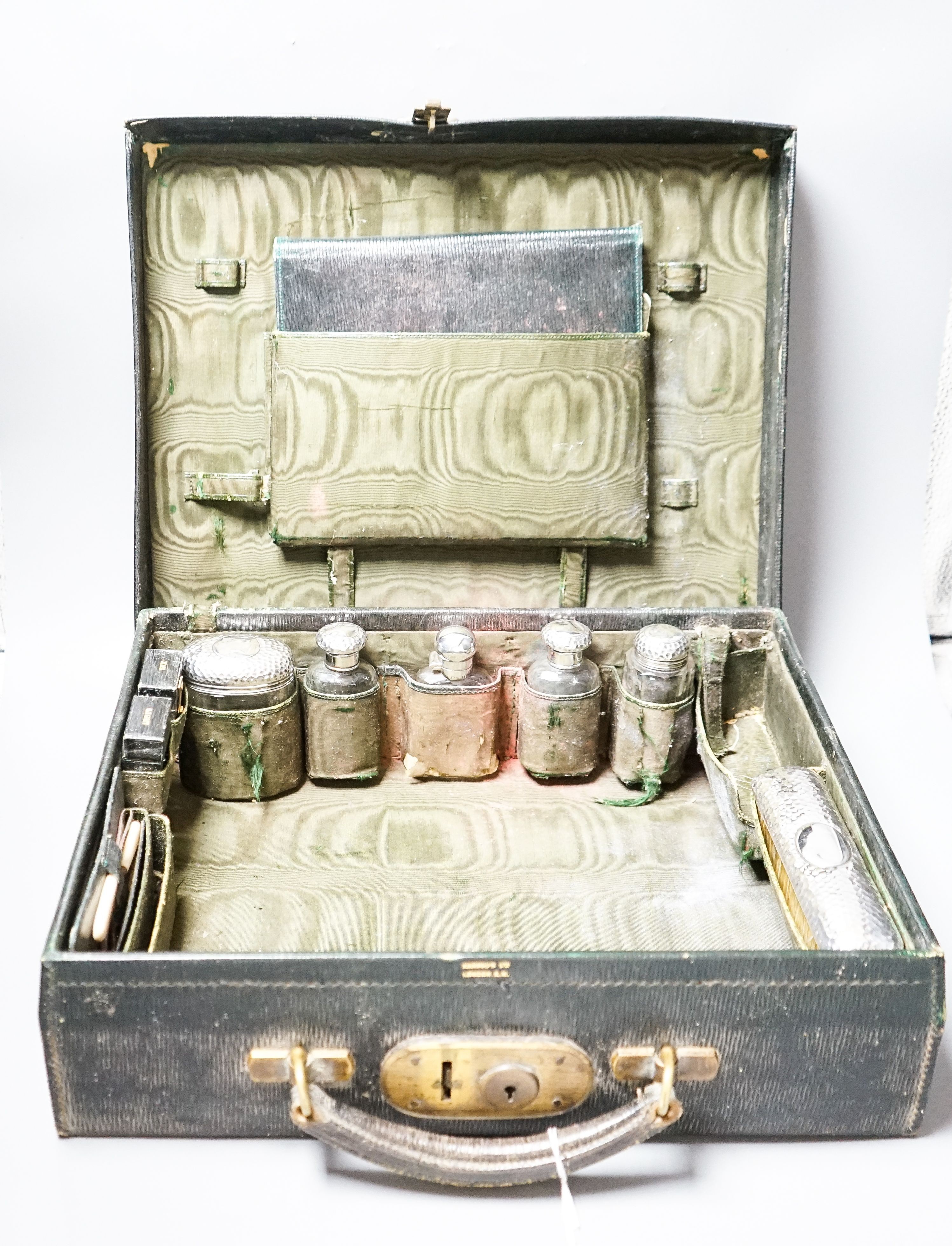 An Edwardian Harrod's traveling toilet case, fitted with six silver mounted toilet accessories, including an associated hip flask, case 40.3cm.